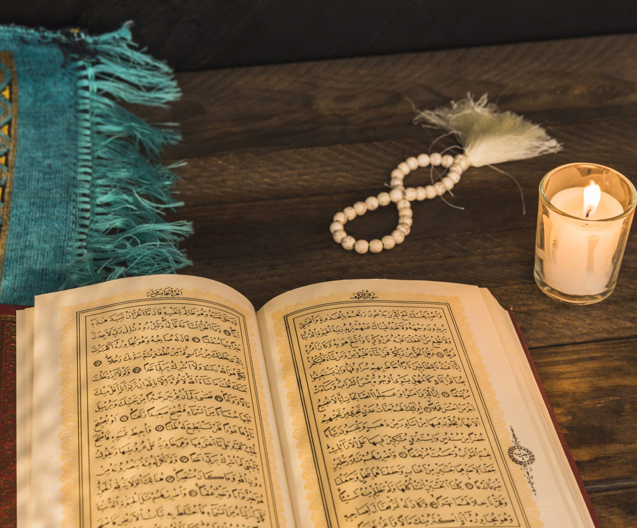 prayer-beads-candle-near-religious-book
